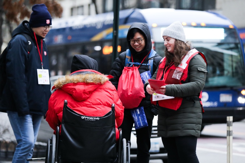 Volunteers doing street outreach with someone in a wheelchair
